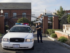 FILE - In this Sept. 17, 2013, file photo, a police officer stands by a locked gate at the Washington Navy Yard in Washington, the day after a gunman launched an attack inside the Washington Navy Yard. The Defense Department is poised to take over background investigations for the federal government, using increased automation and high-tech analysis to tighten controls and tackle a massive backlog of workers waiting for security clearances, according to U.S. officials. The change aims to fix a system whose weaknesses were exposed by the case of a Navy contractor who gunned down a dozen people at Washington's Navy Yard in 2013. He was able to maintain a security clearance despite concerns about his mental health and an arrest that investigators never reviewed.