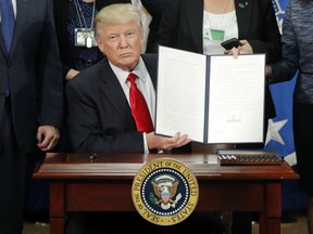 FILE - President Donald Trump holds up an executive order for border security and immigration enforcement improvements after signing the order during a visit to the Homeland Security Department headquarters in Washington, on Jan. 25, 2017. A survey conducted by The Associated Press-NORC Center for Public Affairs Research and MTV finds that parents and their kids agree about a lot of things when it comes to politics. Most in both generations disapprove of Trump, and 55 percent say they usually see eye to eye about politics.