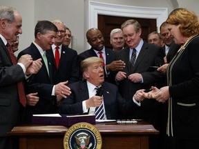 FILE - In this May 24, 2018, file photo, President Donald Trump hands a pen to Sen. Heidi Heitkamp, D-N.D., right, after signing the "Economic Growth, Regulatory Relief, and Consumer Protection Act," in the Roosevelt Room of the White House in Washington. Heitkamp, in one of the most challenging Senate re-election races this year, mixes pro-Trump record with Democratic leanings, though describing them as non-partisan and not part of Democratic resistance movement.
