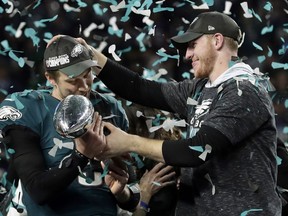 FILE - In this Feb. 4, 2018 photo, Philadelphia Eagles quarterback Carson Wentz, right, hands the Vincent Lombardi trophy to Nick Foles after winning the NFL Super Bowl 52 football game against the New England Patriots in Minneapolis. The Eagles won 41-33.  President Donald Trump has called off a visit by the Philadelphia Eagles to the White House Tuesday due to the dispute over whether NFL players must stand during the playing of the national anthem. Trump says in a statement that some members of the Super Bowl championship team "disagree with their President because he insists that they proudly stand for the National Anthem, hand on heart." Trump says the team wanted to send a smaller delegation, but fans who planned to attend "deserve better."