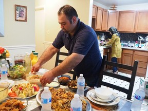In this May 25, 2018, photo, Syrian refugee Majed Abdalraheem, 29, sets the table at his home in Riverdale, Md., as he and his wife, Walaa Jadallah, prepare for the Iftar meal during Ramadan. Abdalraheem is a chef with a meal delivery company called Foodhini.