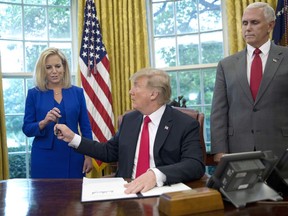 In this June 20, 2018, photo, President Donald Trump gives the pen he used to sign the executive order to end family separations at the border to Homeland Security Secretary Kirstjen Nielsen, left, as Vice President Mike Pence, right, watches in the Oval Office of the White House in Washington. Nielsen has one hard-earned presidential signing pen, receiving hers after Trump used it to sign the executive order. By the time Trump reversed his policy Wednesday, Nielsen had been both yelled at and praised by Trump and pilloried for repeating his falsehoods.