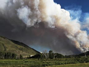 Smoke from a wildfire can be seen rising from the Medicine Bow National Forest near Woods Landing, Wyo., Wednesday, June 13, 2018. Several thousand people in Colorado and Wyoming fled multiple wildfires scorching the drought-stricken U.S. West on Wednesday.