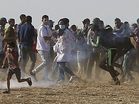 Volunteer paramedic Razan Najjar, 21, center, is seen before being shot in her chest by Israeli troops while running with protesters to take cover from teargas fired by Israeli troop near the Gaza Strip's border with Israel, during a protest east of Khan Younis, Gaza Strip, Friday, June 1, 2018. Najjar was fatally shot in the chest and died later at hospital, the Health Ministry said.