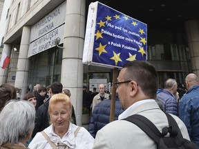 People gather in front of the European Union office to protest the government's judiciary policy, in Warsaw, Poland, Tuesday, June 26, 2018. Poland faced questions from its European Union partners Tuesday over an overhaul of its judicial system that is seen as a violation of Western democratic standards, while also taking the opportunity to explain its reasons for the contested changes. The placard reads "Only under this sign Poland will be Poland and a Pole will be a Pole".