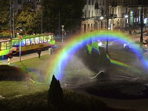 Color are reflected on a streetcar driving past a light and water rainbow installation on the night before a gay pride parade, in downtown Warsaw, Poland, Friday, June 8, 2018.