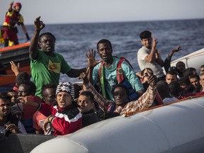 RETRANSMISSION TO ADD AP STYLE SIGN-OFF BYLINE - Migrants aboard a rubber dinghy off the Libyan coast wave to rescuers aboard the Open Arms aid boat, of Proactiva Open Arms Spanish NGO, Saturday, June 30, 2018. 60 migrants were rescued as Italy's right-wing Interior Minister Matteo Salvini tweeted: "They can forget about arriving in an Italian port."