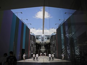 Chinese people are reflected on a glass panels of the Apple Store as they walk through the capital city's popular shopping mall in Beijing, Thursday, June 28, 2018. China's government defended its trade record as a benefit to the world in a new effort Thursday to defuse U.S. and European pressure over market access and technology policy.
