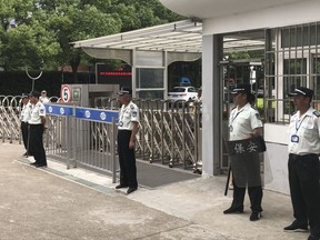Security guards stand at a school entrance gate in Shanghai, China, Thursday, June 28, 2018. Police say a 29-year-old man using a kitchen knife attacked three boys and a mother near a school in Shanghai on Thursday, killing two of the children. (AP Photo)