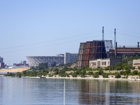 The Red October factory buildings, right, are seen next to the new the World Cup stadium, left, on the banks of the Volga River in Volgograd, Russia, Friday, June 15, 2018. Workers at the Red October steelworks in Volgograd are angry over temporary layoffs linked to the World Cup and deeper financial troubles at the factory, which sits in the shadow of the Volgograd Arena tournament venue. The situation reflects difficult daily reality in Russia even as President Vladimir Putin seeks to showcase his economic successes.