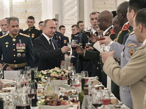 Russian President Vladimir Putin, centre, toasts with the graduates of Russian military academies in the Kremlin in Moscow, Russia, Thursday, June 28, 2018. Putin boasted about his country's prospective nuclear weapons, saying they are years and even decades ahead of foreign designs. Russian Defense Minister Sergei Shoigu is left.
