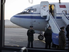 FILE - In this Dec. 19, 2011, file photo, North Korean officials wait for passengers to board an Air China flight at Pyongyang airport in Pyongyang, North Korea. State-owned Air China will resume flights to North Korea's capital on Wednesday, June 6, 2018, an airline employee said, amid preparations for a possible meeting between U.S. President Donald Trump and North Korean leader Kim Jong Un.