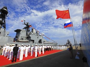 FILE - In this Sept. 12, 2016, file photo released by China's Xinhua News Agency, officers and sailors of China's People's Liberation Army (PLA) Navy hold a welcome ceremony as a Russian naval ship arrives in port in Zhanjiang in southern China's Guangdong Province. Just a month after beginning his new term in office, Russian President Vladimir Putin is heading to China for a state visit in June 2018, underscoring how mounting U.S. pressure is drawing the two countries increasingly close.
