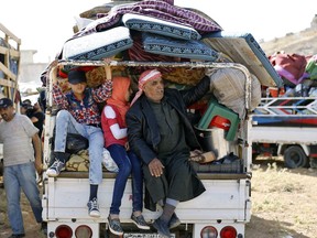 Syrian refugees in the back of a pickup truck get ready to cross into Syria from the eastern Lebanese border town of Arsal, Lebanon, Thursday, June 28, 2018. Dozens of Syrian refugees in Lebanon have started to cross the border, going back home to war-torn Syria.