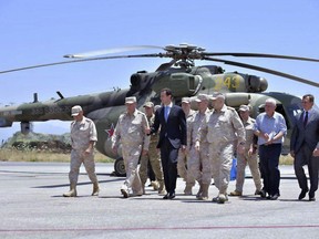 FILE - In this June 27, 2017, file photo, released by the official Facebook page of the Syrian Presidency, Syrian President Bashar Assad, center, inspects the Russian Hemeimeem air base in the province of Latakia, Syria. Russia's deployment near the Syria-Lebanon border this week and its withdrawal a day later after protests from the militant Hezbollah group reveals some of the uneasy relations between allies of President Bashar Assad who joined the country's civil war to back him. The move comes amid calls by Russia for foreign countries to withdraw troops from Syria while Tehran says it presence will remain as long as there are threats from terrorists. (Syrian Presidency via Facebook, File)