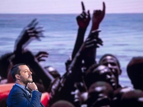 Italian Interior Minister Matteo Salvini, backdrop with a photograph of migrants being rescued at sea, attends a talk show on RAI state television, in Rome, Wednesday, June 20 2018.