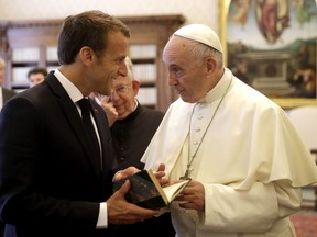 Pope Francis and with French President Emmanuel Macron, left, exchange gifts on the occasion of their private audience, at the Vatican, Tuesday, June 26, 2018.