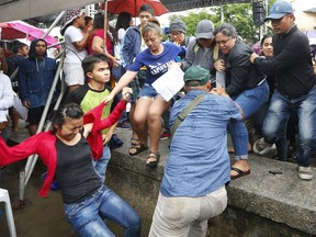 Protesters are roughed up by plainclothes police after heckling Philippine President Rodrigo Duterte at the 120th Philippine Independence Day celebration at the Emilio Aguinaldo Shrine at Kawit, Cavite province south of Manila, Philippines Tuesday, June 12, 2018. Duterte's speech was marred by protesters who heckled him with shouts of "traitor!" and "Oust Duterte!"