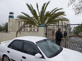 An investigator attends to the gates of a mosque in Malmesbury, near Cape Town, South Africa Thursday June 14 2018.  South African police say a man with a knife fatally stabbed two people and wounded several others at a mosque near Cape Town before police shot and killed the attacker.