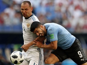 Uruguay's Luis Suarez, right, and Russia's Sergei Ignashevich fight for the ball during the group A match between Uruguay and Russia at the 2018 soccer World Cup at the Samara Arena in Samara, Russia, Monday, June 25, 2018.