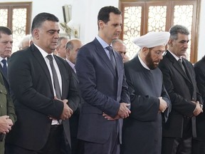 In this photo released by the Syrian official news agency SANA, shows Syrian President Bashar Assad, centre, prays on the first day of Eid al-Fitr, that marks the end of the Muslim holy month of Ramadan, in Tartous, Syria, Friday, June 15, 2018. (SANA via AP)