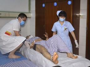 In this photo released by Xinhua News Agency, hospital workers attend to a person injured in a coach-truck collision accident in Hengdong County, central China's Hunan Province, Saturday, June 30, 2018. Police says the death toll from the Friday, June 29, 2018 head-on collision between a passenger coach and a truck on a highway in central China has risen to more than a dozen.