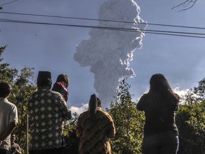 Residents watch as Mount Merapi erupts in Cangkringan, Yogyakarta, Indonesia, Friday, June 1, 2018. The country's most volatile volcano shot a towering plume of ash about 6 kilometers (4 miles) high Friday in an eruption authorities said lasted two minutes.