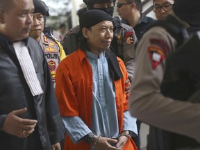 Islamic cleric Aman Abdurrahman, center, is escorted by police officers upon arrival for his trial at South Jakarta District Court in Jakarta, Indonesia, Friday, June 22, 2018. An Indonesian court has sentenced Abdurrahman to death for ordering Islamic State group-affiliated militants to carry out attacks including the January 2016 suicide bombing at a Starbucks in Jakarta.