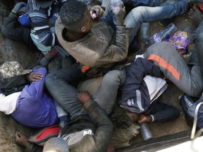 In this Wednesday, May 9, 2018 provided by Liberian Ju Dennis, fellow migrants being expelled from Algeria lie in a truck headed towards the Niger border at Point Zero, from which they must walk south into the Sahara Desert towards the Nigerien border post of Assamaka, 10 miles south. In the open truck, migrants vainly tried to shade their bodies from the sun and hide from the soldiers outside.