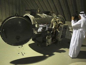 An Emirati journalist films what officials described as a heat exchanger used in the production of rocket fuel that they captured in Marib, Yemen, on display at a military installation in the United Arab Emirates, Tuesday, June 19, 2018. Officials involved in the Saudi-led campaign against Shiite rebels in Yemen known as Houthis showed journalists on Tuesday materiel captured on the battlefield that they alleged show Iran's hand in arming the rebels. Iran long has denied arming the Houthis, despite reports by the United Nations, Western countries and outside groups linking them to the rebels' arsenal.