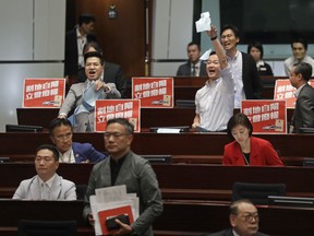 Two pro-democracy lawmakers, at the back, shout and tear up the government documents after a controversial bill had passed at legislative chamber In Hong Kong, Thursday, June 14, 2018. The Hong Kong Legislative Council had passed a controversial bill on Thursday on the co-location checkpoint arrangements for a cross-border Guangzhou-Shenzhen-Hong Kong express rail link, a high speed rail link that connects Hong Kong and mainland Chinese cities.