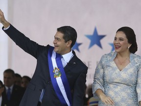 FILE - In this Jan. 27, 2018 file photo, Honduran President Juan Orlando Hernandez acknowledges supporters accompanied by his wife Ana Garcia, during his presidential inaugural ceremony at the National Stadium in Tegucigalpa, Honduras. Honduras' ruling party said Wednesday, June 13, that it will cooperate with prosecutors' investigation into allegations public funds were illegally diverted to the 2013 campaign of President Hernandez.