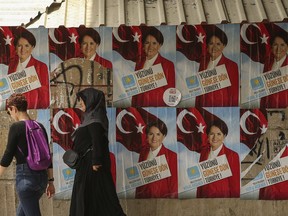 People walk past posters of Meral Aksener, the presidential candidate of nationalist opposition IYI (Good) Party, in Istanbul, Thursday, June 21, 2018. Aksener, 61, who split from Turkey's main nationalist party following a spat with its leader over his support to Turkey's President Recep Tayyip Erdogan. Turkey holds parliamentary and presidential elections on June 24, 2018.