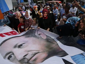 In this photo taken on Monday, June 18, 2018, supporters wave a banner with a picture of Turkey's President Recep Tayyip Erdogan, during a gathering of his ruling Justice and Development Party (AKP) in Istanbul . Turkish voters are heading to the polls June 24 to vote in crucial presidential and parliamentary elections that could either solidify President Recep Tayyip Erdogan's grip on power or unsettle his political ambitions.