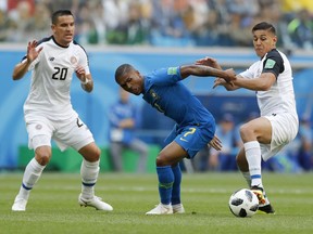 Brazil's Douglas Costa, centre, battles for the ball with Costa Rica's Oscar Duarte, right, as Costa Rica's David Guzman watches during the group E match between Brazil and Costa Rica at the 2018 soccer World Cup in the St. Petersburg Stadium in St. Petersburg, Russia, Friday, June 22, 2018.