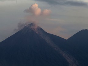 Volcan de Fuego, or Volcano of Fire, blows outs a cloud of ash, as seen from Escuintla, Guatemala, Tuesday, June 5, 2018. at right inactive Acatenango volcano. People of the villages skirting Guatemala's Volcano of Fire began mourning the few dead who could be identified after an eruption killed dozens by engulfing them in floods of searing ash and mud.