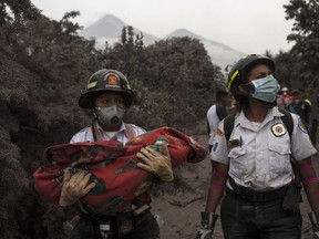 A firefighter carries the body of a child recovered near the Volcan de Fuego, which means in Spanish Volcano of Fire, in Escuintla, Guatemala, Monday, June 4, 2018. A fiery volcanic eruption in south-central Guatemala sent lava flowing into rural communities, killing dozens.