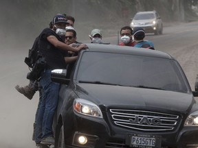 Rescuers and journalists evacuate the disaster zone as a column of smoke and ash rises from the area where lava flowed down the Volcan de Fuego, or "Volcano of Fire," in Escuintla, Guatemala, Tuesday, June 5, 2018. Guatemala's disaster agency issued evacuation order for towns near Volcano of Fire after increased activity. The fiery volcanic eruption in south-central Guatemala killed scores as rescuers struggled to reach people where homes and roads were charred and blanketed with ash.
