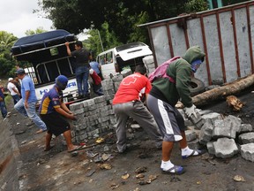 Anti-government protesters remove a roadblock they created so commercial vehicles can pass in Jinotepe, Nicaragua, Tuesday, June 12, 2018. Protests began in mid-April in response to changes to the social security system, but expanded to call for President Daniel Ortega's exit from power.
