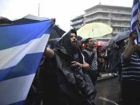 Protesters hold Greek flags and shout slogans during a rainfall, as they demonstrate against Greece's name deal with neighboring Macedonia in the northern port city of Thessaloniki , Greece, on Wednesday, June 27, 2018.