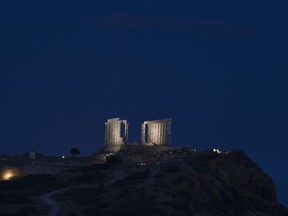 In this Thursday, June 28, 2018 photo, the columns of the 444 BC ancient marble Temple of Poseidon are illuminated, at Cape Sounion, in south of Athens. Greece has significantly improved its economy as it heads toward the end of its bailout program in August, but its debt pile will remain difficult to manage in the long term, the International Monetary Fund said Friday.