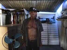 In this June 13, 2018 photo, 75-year-old retiree Angel Santos Rivera, who doesn't have social security income and survives mainly on food stamps, stands in his home as the hue of a blue tarp spills over his hurricane damaged home in Catano, Puerto Rico. Blue tarps or sturdier plastic sheets installed by the U.S. Army Corps of Engineers are still widely visible around the island, though FEMA and local government agencies say they can't say for certain how many roofs still need to be replaced.