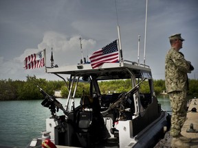In this Monday, June 4, 2018 photo, reviewed by U.S. military officials, a Coast Guard man stands on a jetty at the Guantanamo Bay U.S. Naval Base, Cuba. President Donald Trump's order in January to keep the Guantanamo jail open, and allow the Pentagon to bring new prisoners there, is prompting military officials to consider a future for the controversial facility.