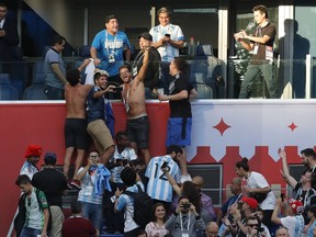 Argentinian soccer former player Diego Armando Maradona, top, stands on the tribune during the group D match between Argentina and Nigeria, at the 2018 soccer World Cup in the St. Petersburg Stadium in St. Petersburg, Russia, Tuesday, June 26, 2018.
