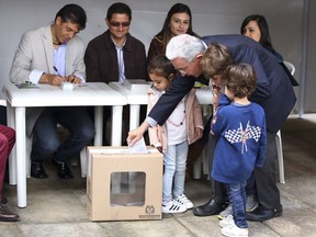 Former President Alvaro Uribe cast his ballot, accompanied by grand children, during the presidential runoff election in Bogota, Colombia, Sunday, June 17, 2018. Voters will choose between Ivan Duque, a young conservative lawmaker, and Gustavo Petro, a leftist former guerrilla and ex-Bogota mayor.