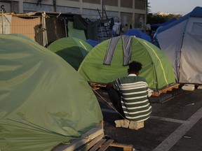 An asylum seeker sits in a camp set by the Baobab aid group, in Rome, Tuesday, June 19, 2018.