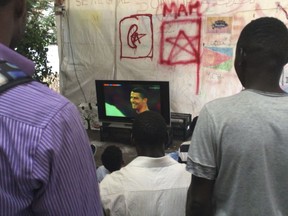 Asylum seekers watch Portugal's Cristiano Ronaldo on a television showing a World Cup soccer match, at a camp set up by the Baobab aid group, in Rome, Friday June 15, 2018. After dramatically blocking humanitarian group's ships from bringing yet even more migrants rescued at sea to Italian ports, Italian Interior Minister Matteo Salvini has proclaimed his next urgent mission: ridding his country of huge numbers of migrants who undertook dangerous treks through African deserts and risky voyages on smugglers' unseaworthy boats across the Mediterranean to reach their dream: a better life in Europe.