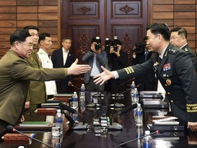 In this photo provided by South Korea Defense Ministry, South Korean Maj. Gen. Kim Do-gyun, right, tries to shakes hands with his North Korean counterpart Lt. Gen. An Ik San during a meeting at the northern side of Panmunjom in the Demilitarized Zone, North Korea, Thursday, June 14, 2018. The rival Koreas were holding rare high-level military talks Thursday to discuss reducing tensions across their heavily fortified border. (South Korea Defense Ministry via AP)