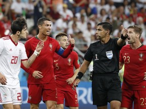 Iran's Sardar Azmoun, left, Portugal's Cristiano Ronaldo argue with referee Enrique Caceres during the group B match between Iran and Portugal at the 2018 soccer World Cup at the Mordovia Arena in Saransk, Russia, Monday, June 25, 2018.