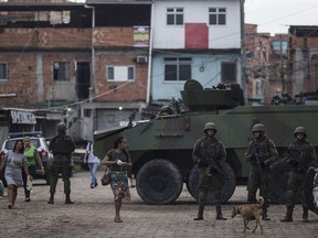 File - In this Feb.20, 2018 file photo, Brazilian marines stand in guard next to an armored vehicle a during surprise operation in Kelson's slum in Rio de Janeiro, Brazil. The head of a military intervention in the state of Rio de Janeiro, Gen. Walter Souza Braga Netto, says the mission includes gathering donations for cash-strapped police forces, teaching officers not to use their smartphones on the job and encouraging businesses to invest with the message that security is improving.